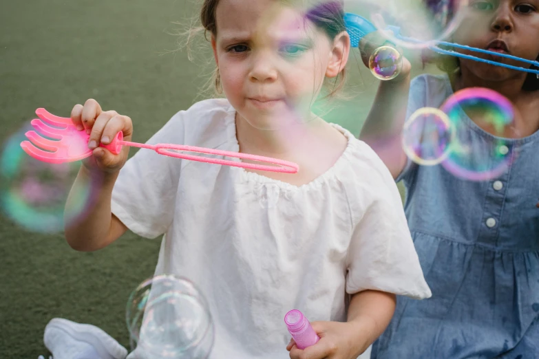 two little girls are playing with soap bubbles, pexels contest winner, young girl playing flute, at a birthday party, max dennison, high quality photo