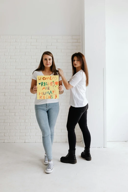 two women standing next to each other holding a sign, a poster, trending on pexels, human design, teen magazine cover, 15081959 21121991 01012000 4k, brunettes