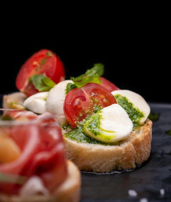 a close up of a sandwich with tomatoes and mozzarella, a portrait, by Carlo Martini, pexels, renaissance, with a black background, square, dolman, mint higlights