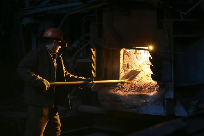 a man that is standing in front of a fire, inside iron and machines, worksafe. dramatic, wielding a crowbar, reuters