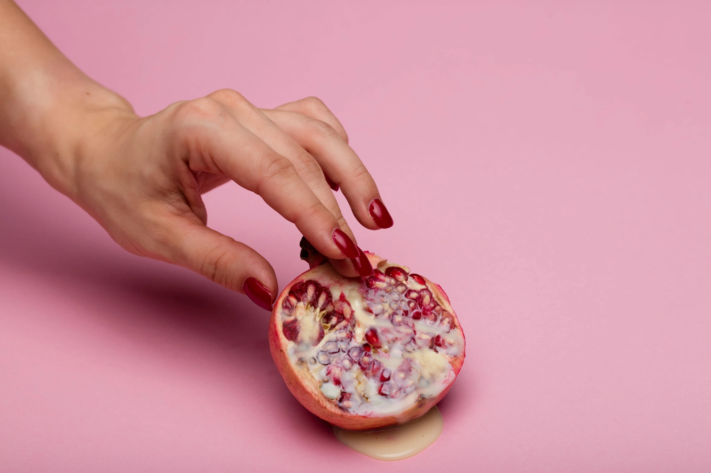 a woman's hand holding a pomegranate on a pink background, by Will Ellis, trending on pexels, arabesque, made of food, porcelain skin ”, cut-away, wolfy nail