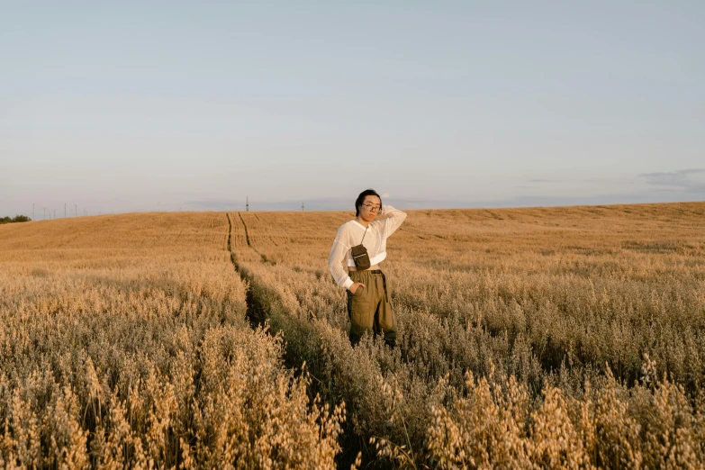 a man standing in a field of tall grass, an album cover, by Emma Andijewska, trending on pexels, girl walking in wheat field, photoshoot for skincare brand, wearing farm clothes, youtube thumbnail