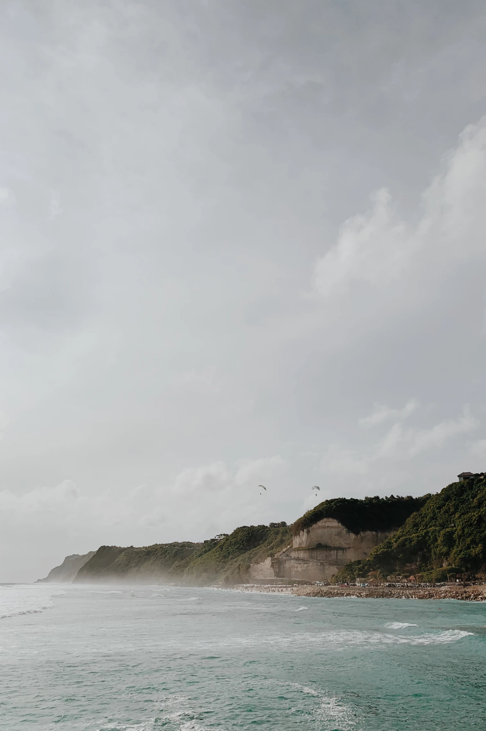 a man riding a surfboard on top of a wave, a matte painting, unsplash, minimalism, trees and cliffs, puerto rico, low clouds after rain, seen from a distance