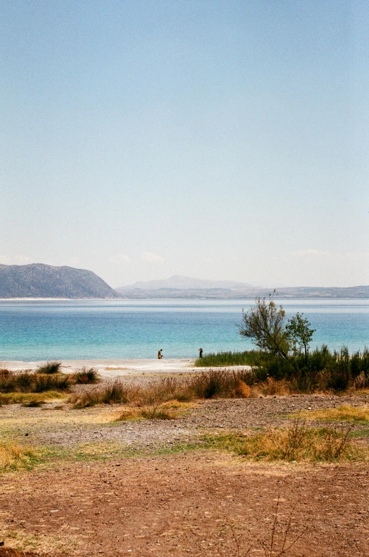 a bench sitting on the side of a beach next to a body of water, hurufiyya, wide landscape, demna gvasalia, portra 160, high resolution photo