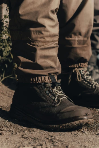 a person standing on top of a dirt field, covert military pants, detailed product shot, hoog detail, brown