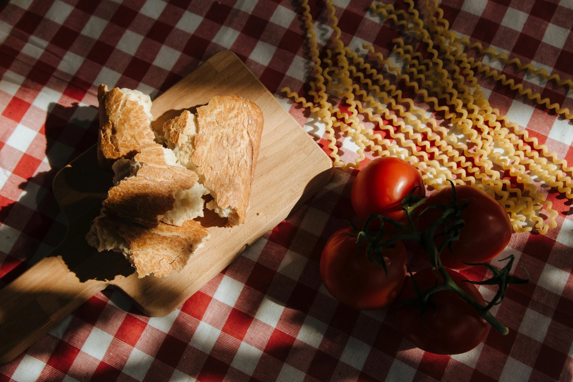 a piece of bread sitting on top of a wooden cutting board, by Julia Pishtar, pexels contest winner, also one tomato slice, on a sumptuous tablecloth, pasta, sun flares