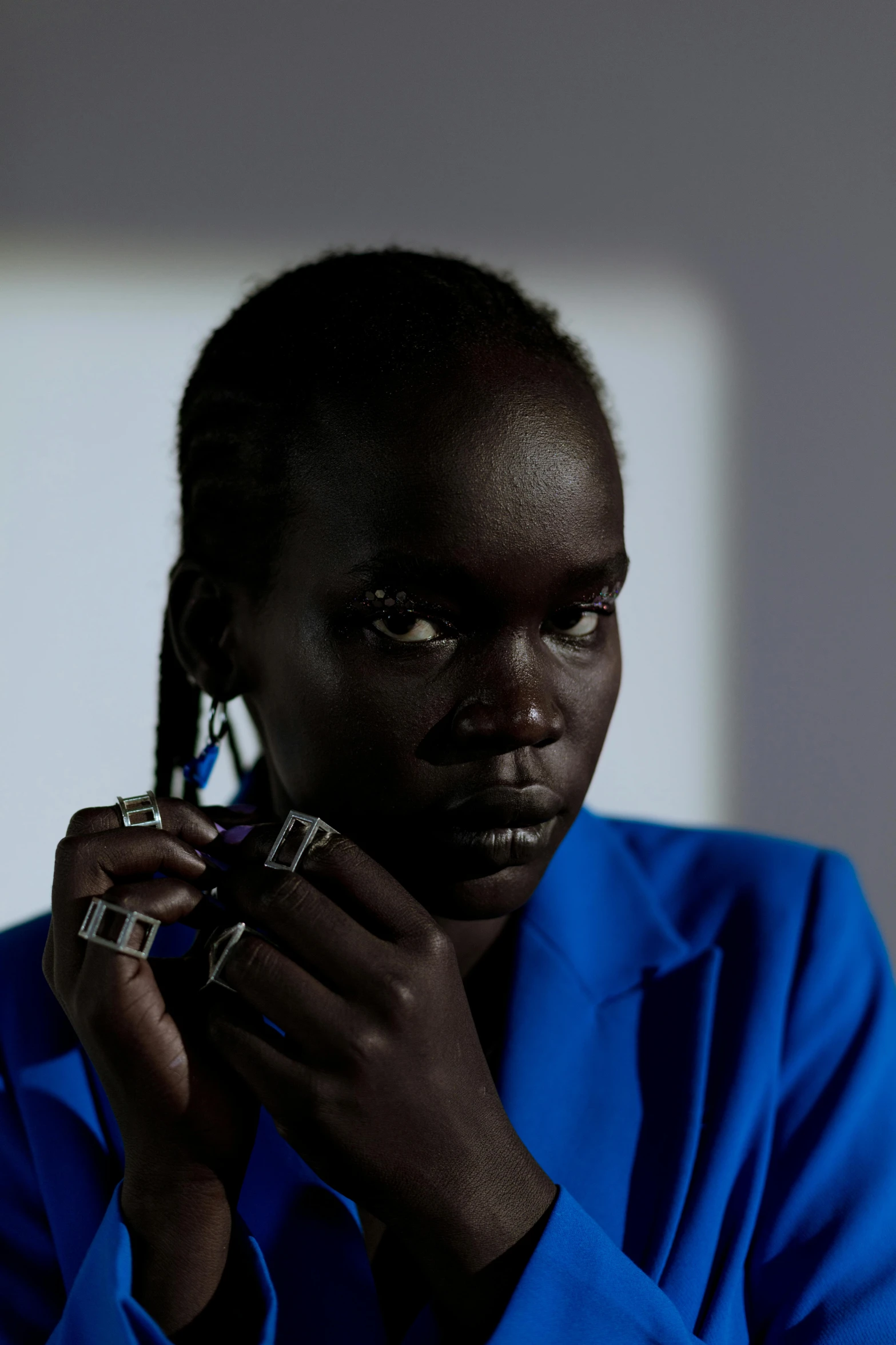 a close up of a person holding a cell phone, afrofuturism, adut akech, wearing blue jacket, earring, slide show