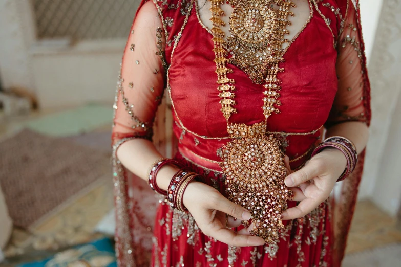 a woman in a red dress holding a piece of jewelry, by Alice Mason, pexels contest winner, hurufiyya, wearing an ornate outfit, wearing a wedding dress, south east asian with long, middle eastern