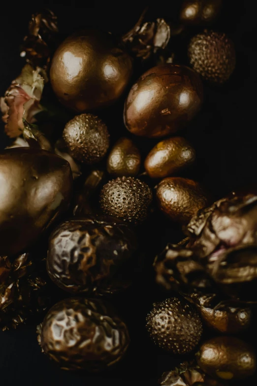 a close up of a bunch of fruit on a table, inspired by Paulus Moreelse, trending on unsplash, baroque, metallic bronze skin, intricate hyperdetail macrophoto, dragon eggs, black gold color scheme