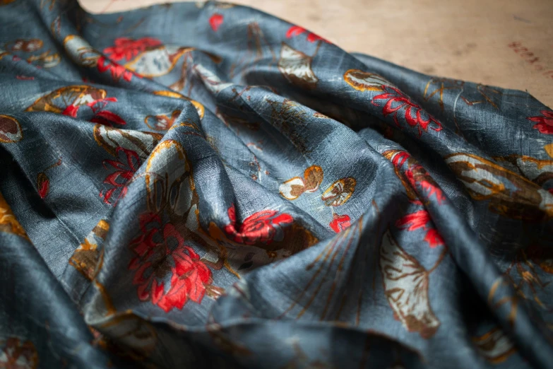 a piece of fabric sitting on top of a table, by Ella Guru, unsplash, renaissance, mediumslateblue flowers, red silk scarf, grey, detail shot