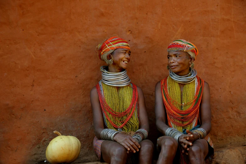a couple of women sitting next to each other, by Dietmar Damerau, pexels contest winner, afrofuturism, beads, both bright and earth colors, 8 k -, nat geo