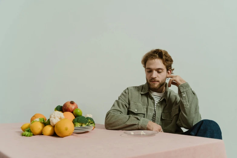a man sitting at a table talking on a cell phone, an album cover, by Carey Morris, pexels contest winner, plates of fruit, thoughtful pose, on a pale background, charlie cox