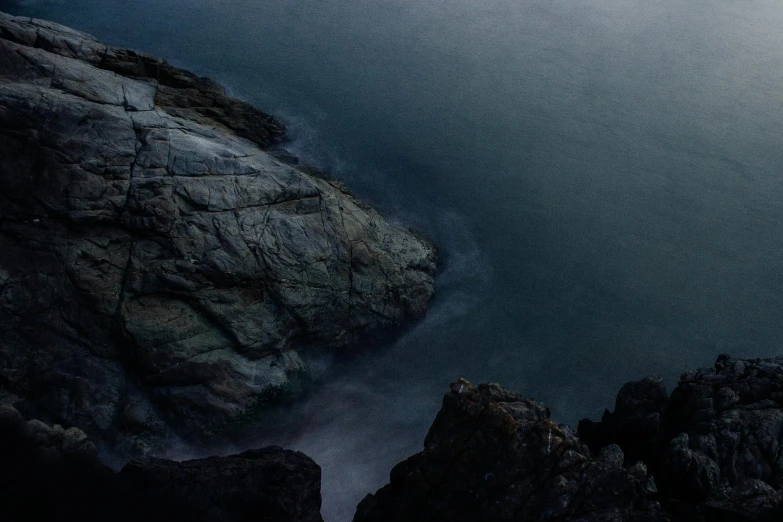 a large body of water next to a rocky shore, inspired by Elsa Bleda, unsplash contest winner, australian tonalism, alessio albi, a high angle shot, long exposure 8 k, looking threatening