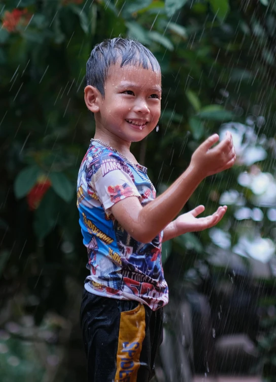 a little boy that is standing in the rain, by Basuki Abdullah, pexels contest winner, smiling and dancing, avatar image, multi - coloured, laos