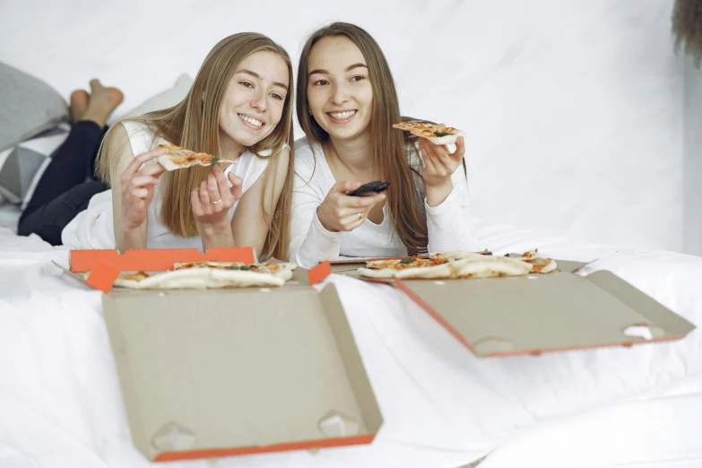 two women sitting on a bed eating pizza, pixabay, pizza box, high school girls, close up photograph, promotional image