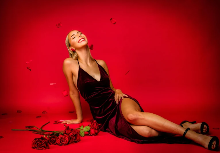 a woman laying on the ground with a rose in her hand, an album cover, by Gavin Hamilton, pexels contest winner, romanticism, red door blonde, laughing, dressed in velvet, sydney sweeney