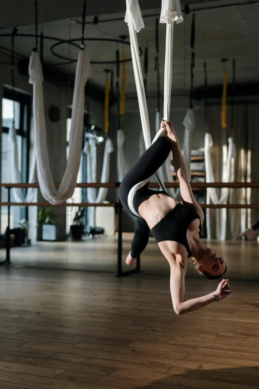 a woman doing a handstand in a dance studio, by Adam Marczyński, pexels contest winner, arabesque, hanging from a hot air balloon, thumbnail, harnesses, anna nikonova aka newmilky