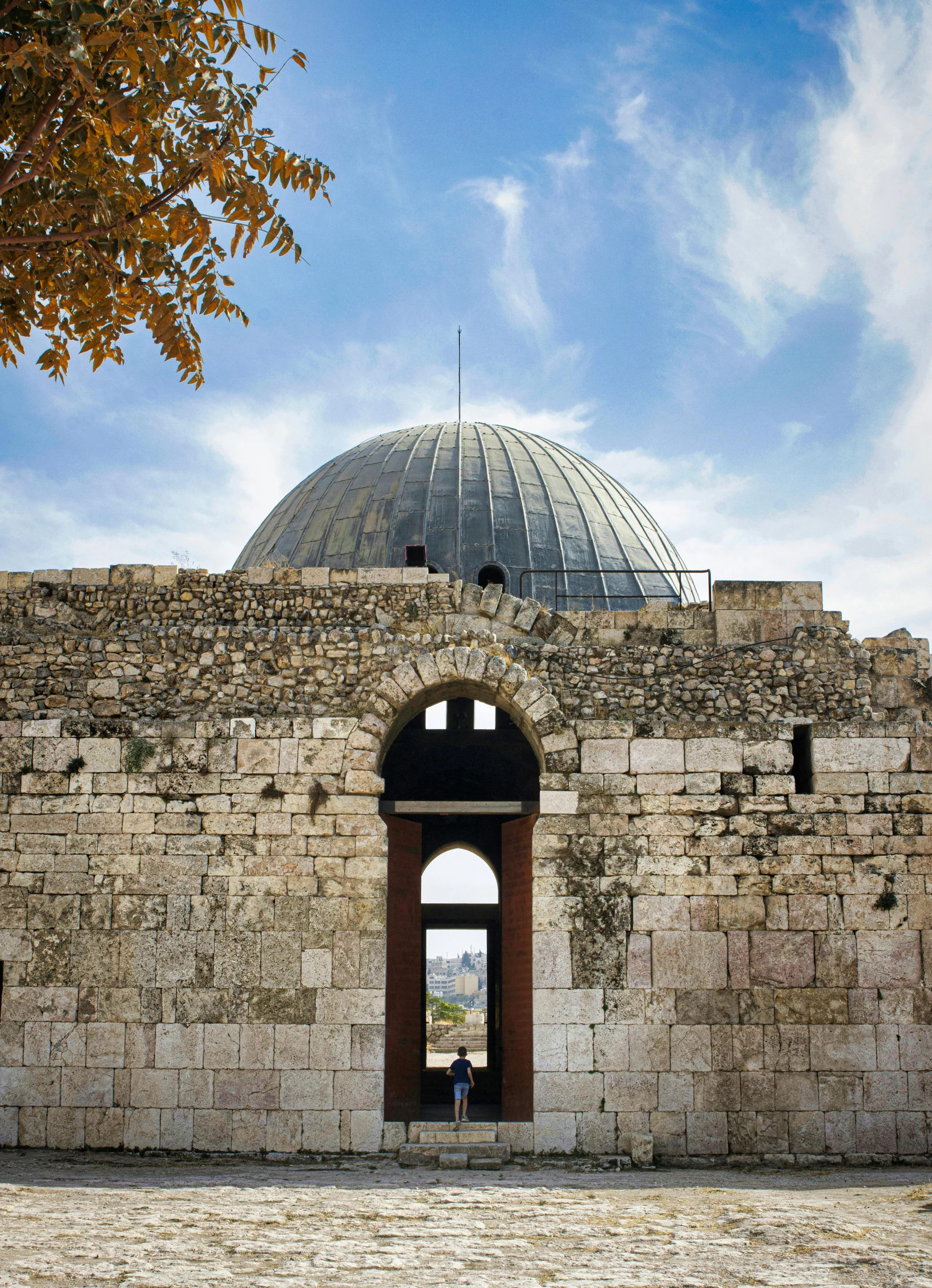 a stone building with a dome on top of it, by Saul Yaffie, dau-al-set, city ruins in the background, circular gate in a white wall, award - winning, split near the left