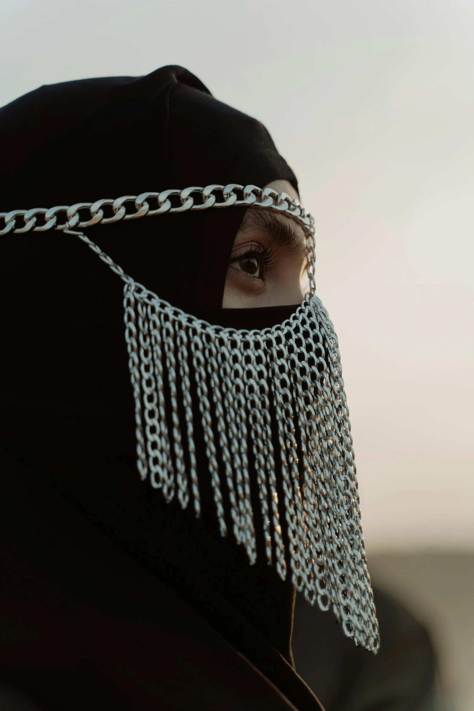 a close up of a person wearing a chain mask, an album cover, hurufiyya, burka, shot on hasselblad, sundown, black