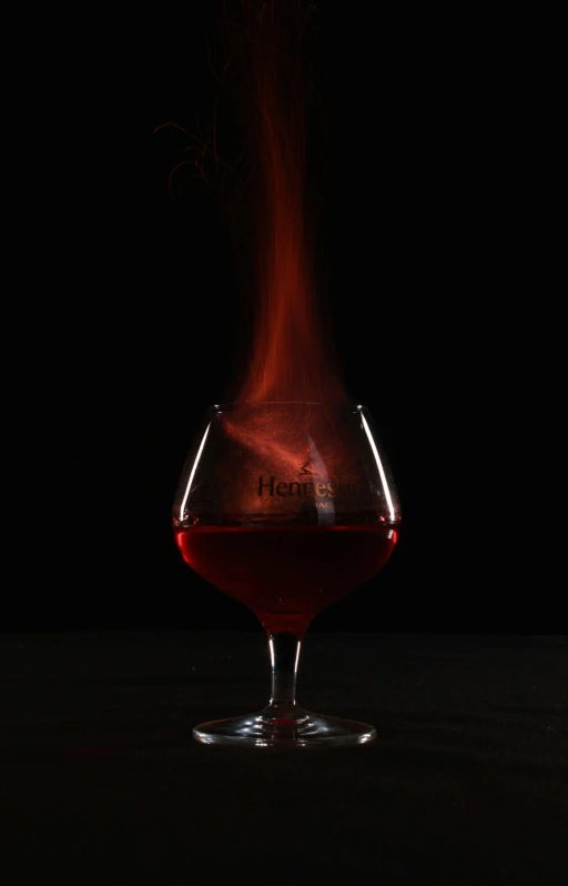 a glass filled with liquid sitting on top of a table, by Jan Rustem, dark thick smokey red fire, hero shot, mead, profile image