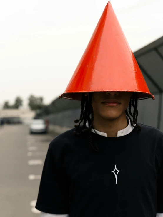 a man with a red cone on his head, an album cover, trending on unsplash, afrofuturism, high quality photo, pyramid hoodvisor, ((portrait)), starry