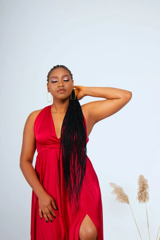 a woman in a red dress posing for a picture, an album cover, by Chinwe Chukwuogo-Roy, trending on pexels, long braids, solid background, high quality upload, black in