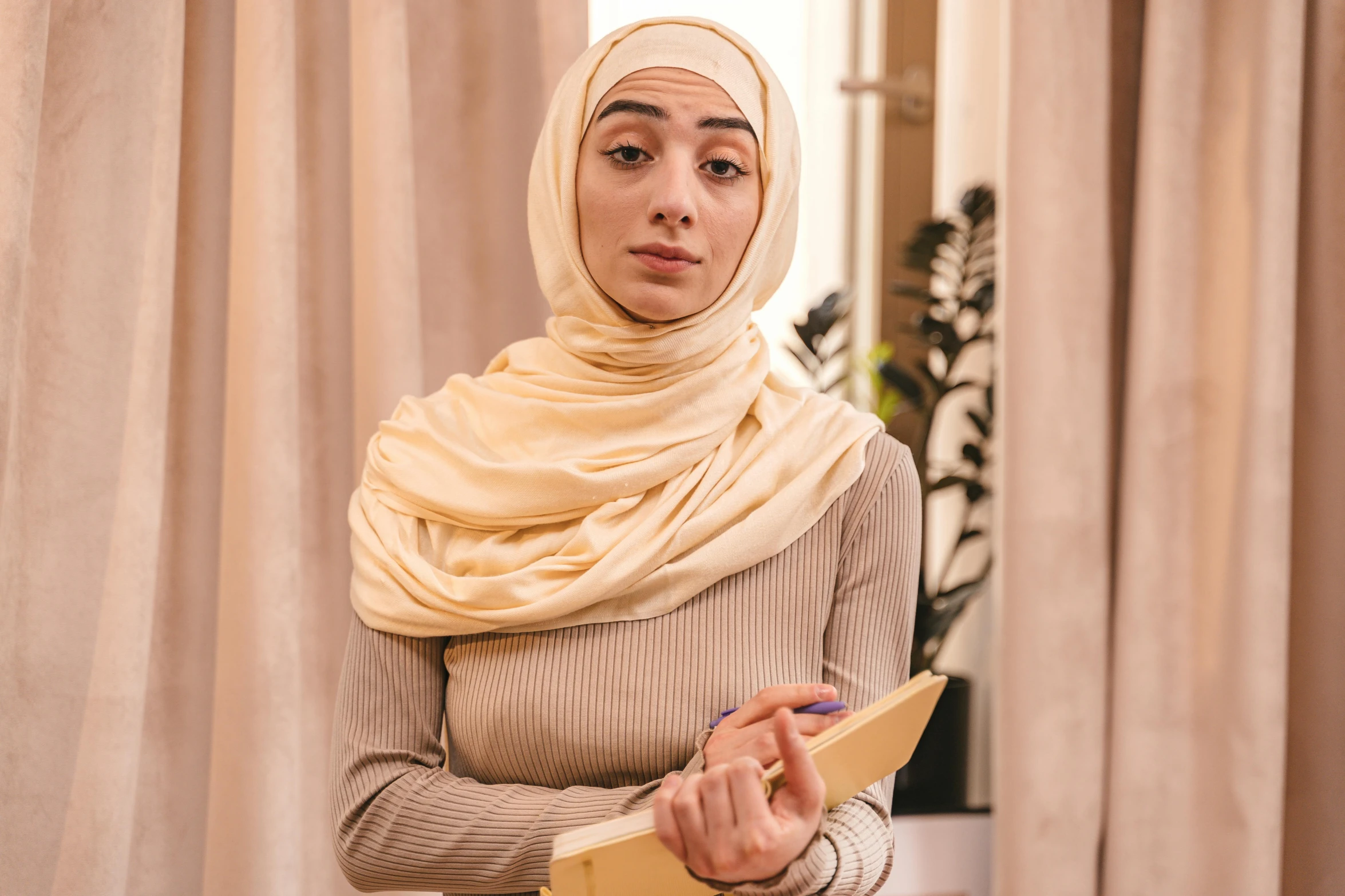 a woman in a hijab holding a book, trending on pexels, hurufiyya, beige, looking confused, actress, middle eastern