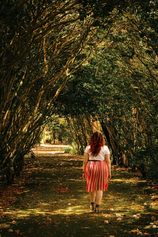 a woman walking down a path lined with trees, inspired by William Stott, pexels contest winner, renaissance, in red gardens, in savannah, stood in a tunnel, branches growing as hair