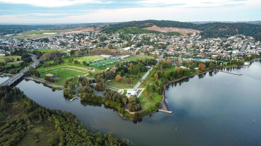 a large body of water next to a lush green hillside, happening, realistic photo of a town, carrington, drone photograph, wide river and lake