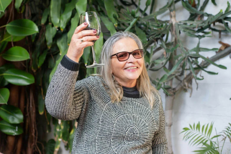 a woman holding up a glass of wine, a portrait, pexels contest winner, silver silver glasses, standing in a cantina, avatar image, gardening