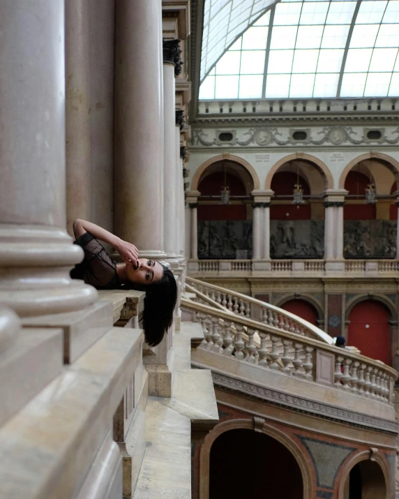 a woman laying on a ledge in a building, by Nina Hamnett, pexels contest winner, conceptual art, vienna state opera house, lgbtq, in the argentine congress, beautiful!!!! museum photo