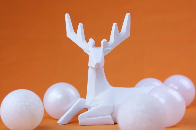 a paper sculpture of a deer surrounded by balls, a marble sculpture, inspired by Rudolph F. Ingerle, relaxed pose, white plastic, festive, white and orange