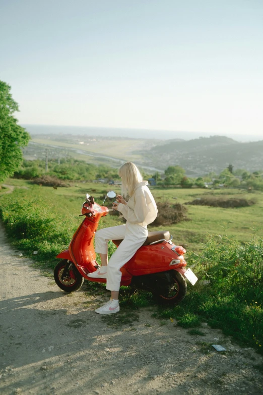 a woman riding on the back of a red scooter, inspired by Elsa Bleda, on a hill, ukraine, cream, overlooking