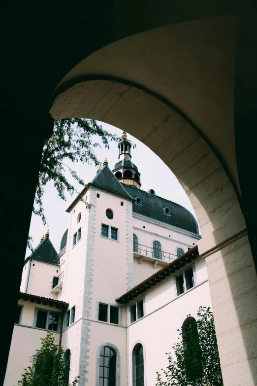 a large white building with a clock tower, inspired by Luis Paret y Alcazar, unsplash, art nouveau, archway, transylvanian castle, view from ground level, bauhaus architecture