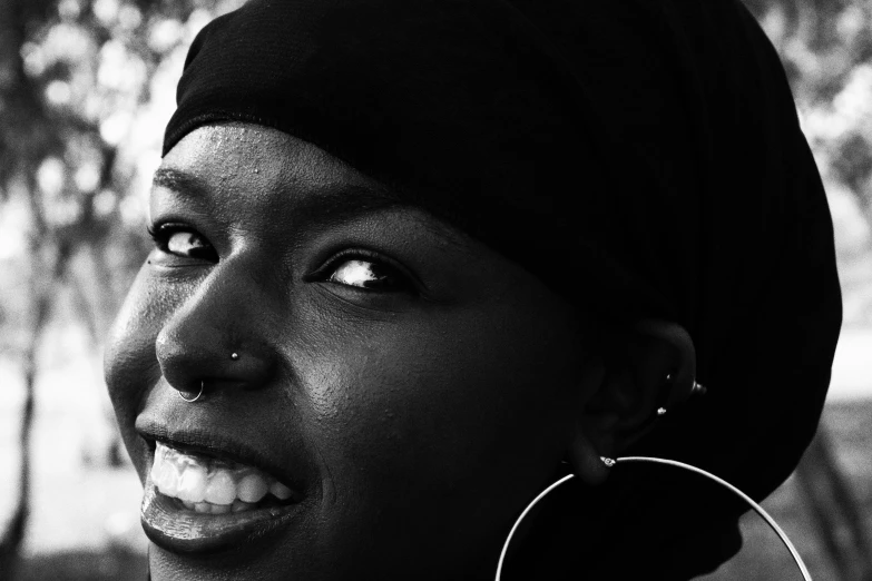 a black and white photo of a woman wearing a turban, a black and white photo, pexels contest winner, hurufiyya, author zima blue, nose ring, photo of a black woman, large black smile