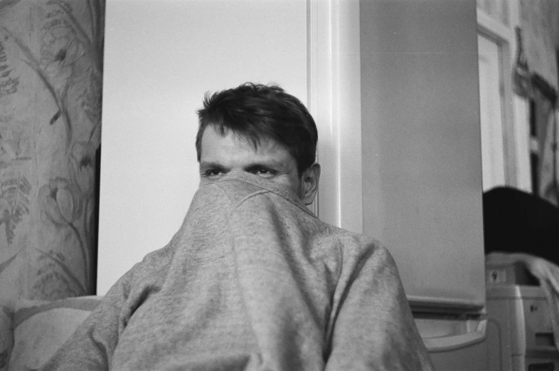 a black and white photo of a man covering his face, by Maurycy Gottlieb, flickr, bauhaus, wearing sweatshirt, fully covered in drapes, vitalik buterin, doing the bateman stare