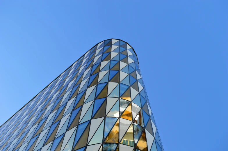 a very tall building with a lot of windows, by Konrad Witz, unsplash, modernism, cone shaped, clear blue sky, bjarke ingels, stone and glass and gold