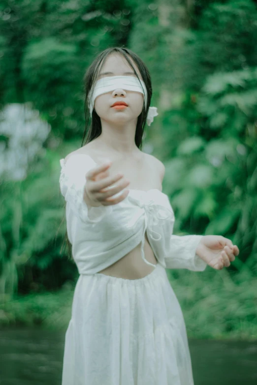 a woman in a white dress with a blindfold on her face, an album cover, by Yu Zhiding, unsplash, aestheticism, ulzzang, white bandages on fists, nature goddess, innocent look