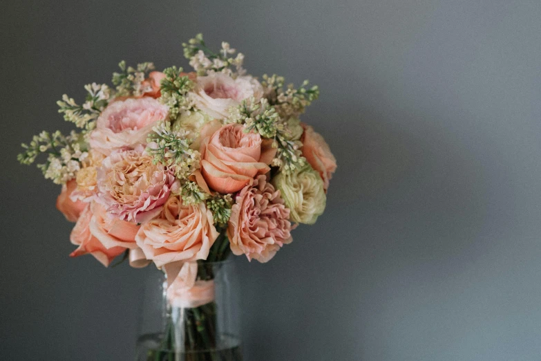 a bouquet of flowers in a vase on a table, in shades of peach, zoomed out, on a gray background, subtle detailing