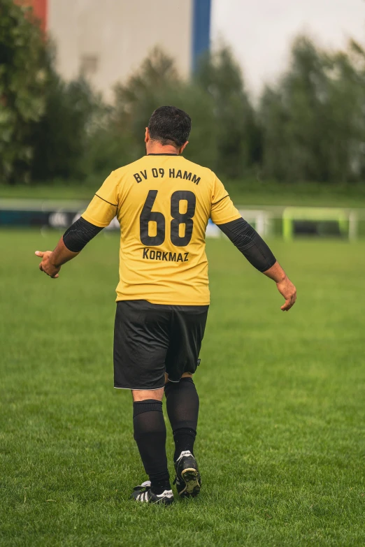 a group of young men playing a game of soccer, a picture, inspired by Hermann Rüdisühli, pexels contest winner, happening, black. yellow, his back is turned, hicham habchi, 8 k movie still