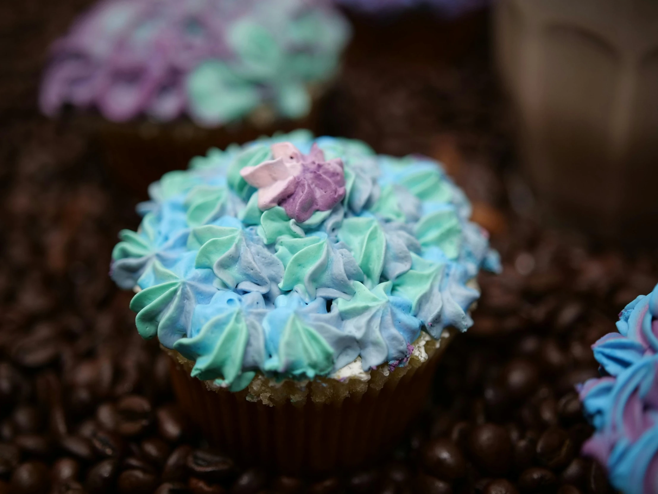 a couple of cupcakes sitting on top of a pile of coffee beans, pexels, blue unicorn, tie-dye, thumbnail, close-up photo