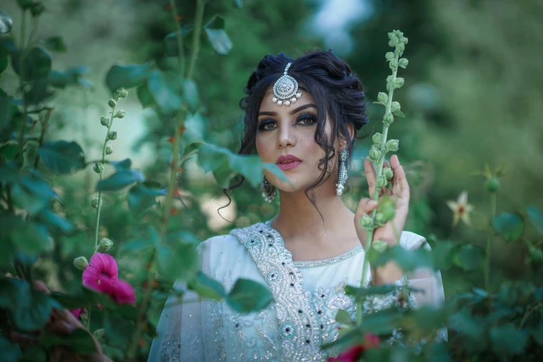 a woman in a white dress surrounded by flowers, inspired by Ambreen Butt, pixabay, traditional makeup, fashion shoot 8k, silver jewellery, cinematic outfit photo