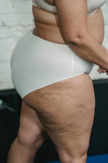 a woman in white underwear standing on a blue mat, by Matija Jama, unsplash, thick thighs, bumpy mottled skin, profile image, largest haunches ever