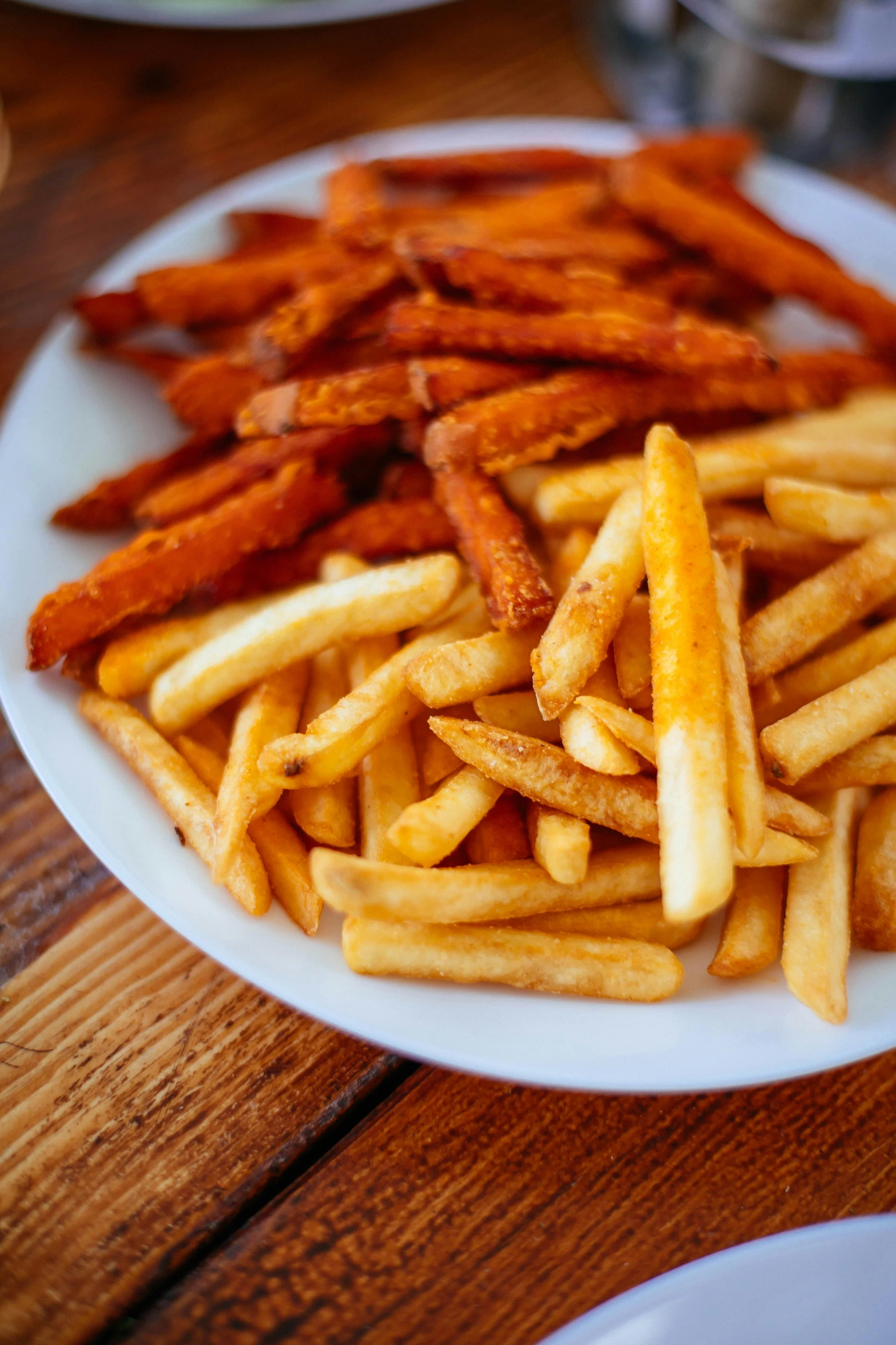 a plate of french fries on a wooden table, orange and white, carson ellis, square, round-cropped