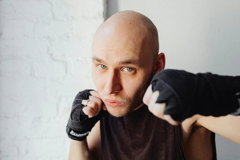 a man with a bald head wearing boxing gloves, a portrait, by Ilya Ostroukhov, pexels contest winner, square masculine jaw, anna nikonova aka newmilky, shaven, dim dingy gym