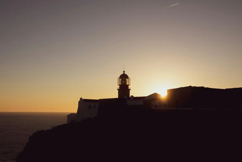 a lighthouse sitting on top of a cliff next to the ocean, by Sebastian Spreng, pexels contest winner, sunset. light shadow, alvaro siza, farol da barra, medium format. soft light