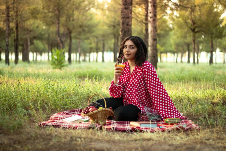 a woman sitting on a blanket holding a glass of wine, pexels, realism, forest picnic, beautiful iranian woman, polka dot, wearing red and yellow clothes