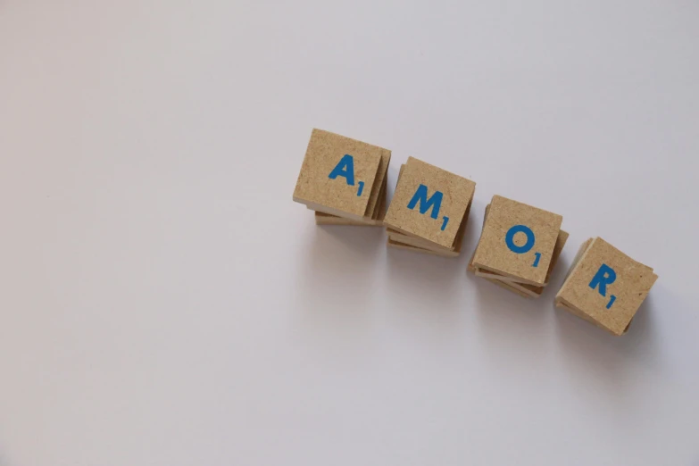 the word amor spelled with scrabbles on a white surface, pixabay, photorealism, 2 4 mm iso 8 0 0 color, anomalisa, minimalist photorealist, blue
