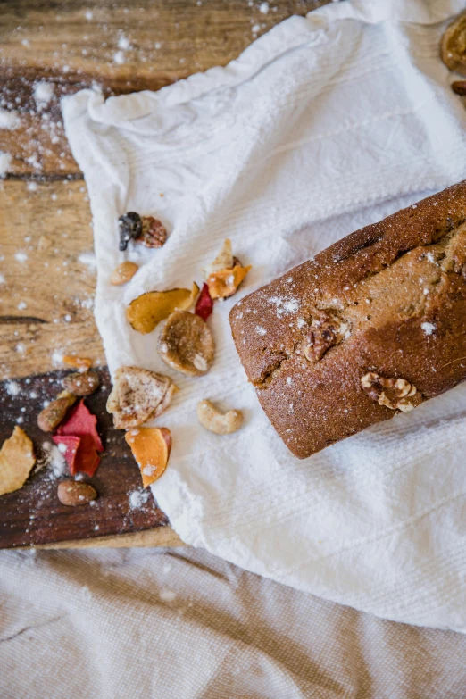 a loaf of bread sitting on top of a white towel, a still life, trending on pexels, renaissance, walnuts, confetti, cake in hand, a wooden