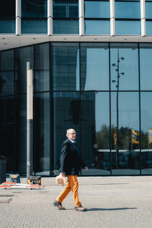 a man walking in front of a large building, unsplash, arbeitsrat für kunst, espoo, older male, elegantly dressed, people at work